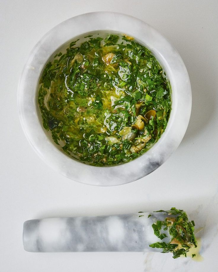 a white bowl filled with greens next to a knife