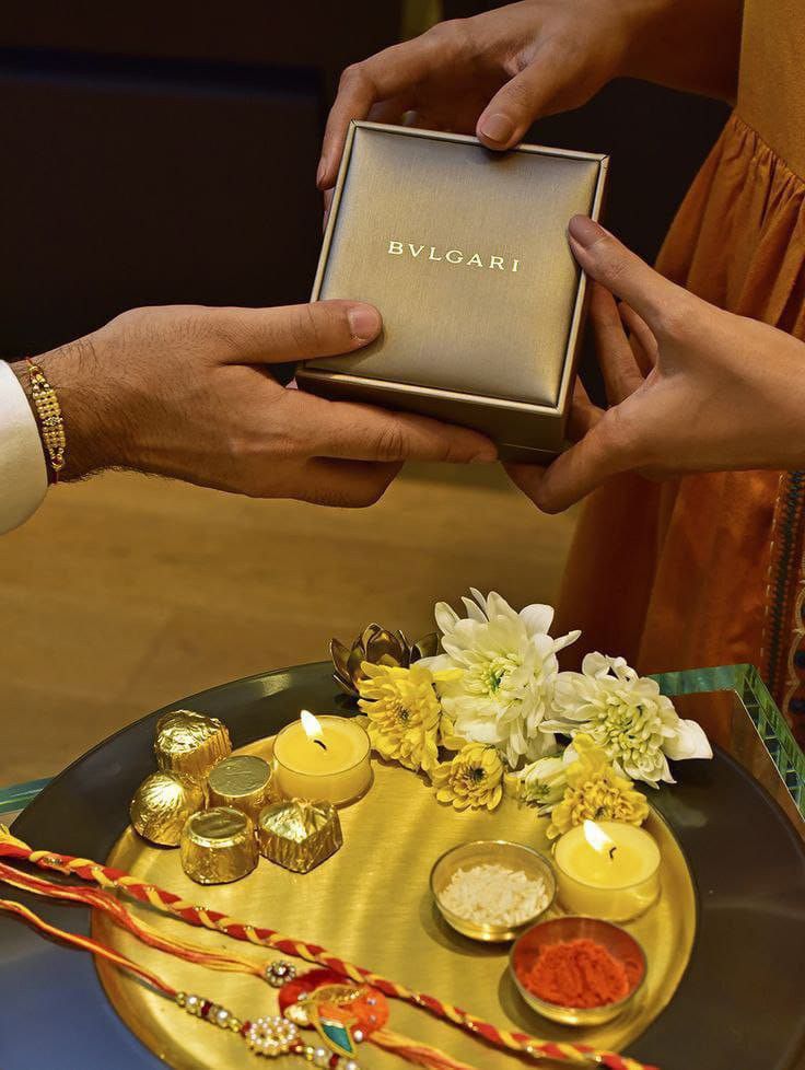 two hands holding a small box with flowers and candles on it while another person holds the box