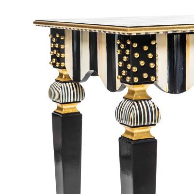 a black and white table with gold trimmings on the top, along with two matching pedestals