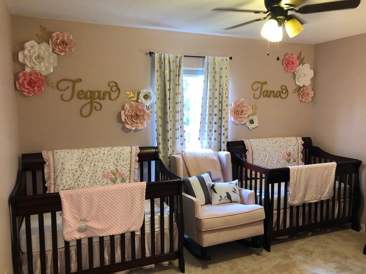 two cribs in a room with flowers on the wall and baby's name written on the wall