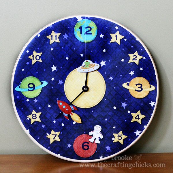 a clock with outer planets painted on the face and numbers around it, sitting on a table