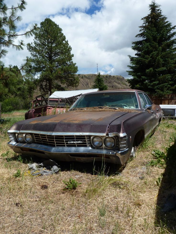 an old rusty car sitting in the grass