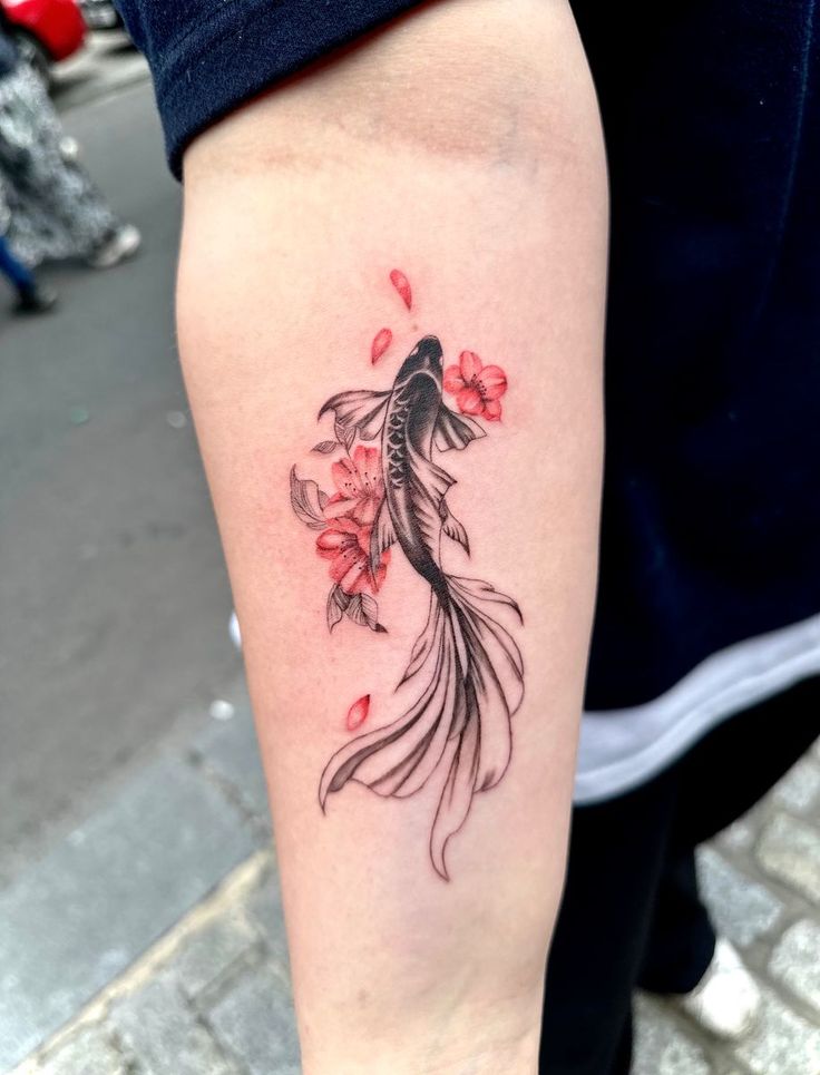 a woman with a tattoo on her arm has a koi fish and red flowers