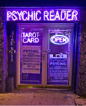 the psychic reader is lit up in purple and blue neon lights on the front door