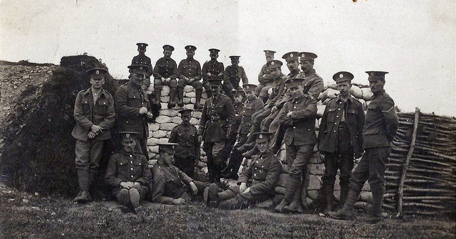 a group of men standing next to each other in front of a pile of hay