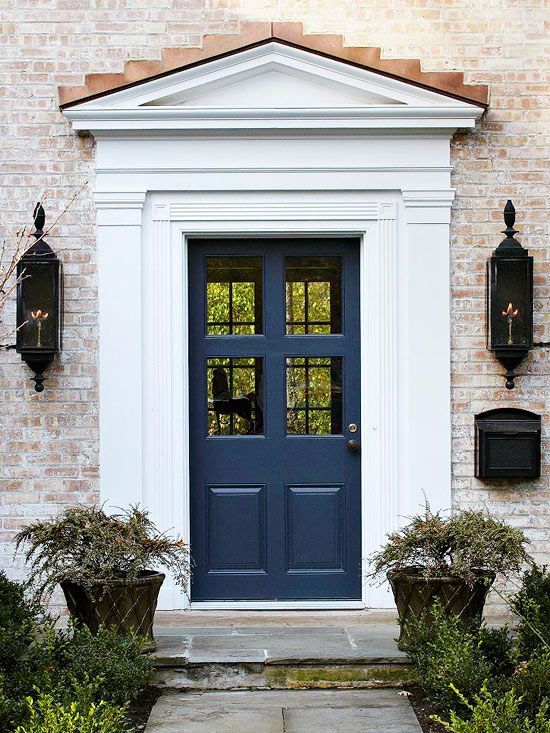 a blue front door with two planters on either side