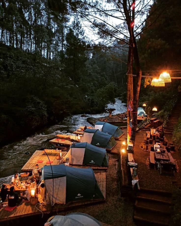 tents are set up next to a river at night