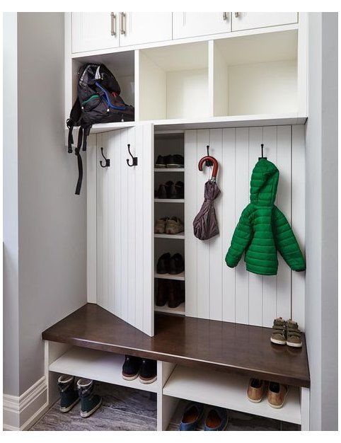 a coat rack with two coats hanging on it's sides and some shoes underneath