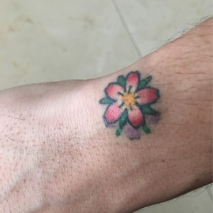 a person with a flower tattoo on their left arm and wrist is looking at the camera