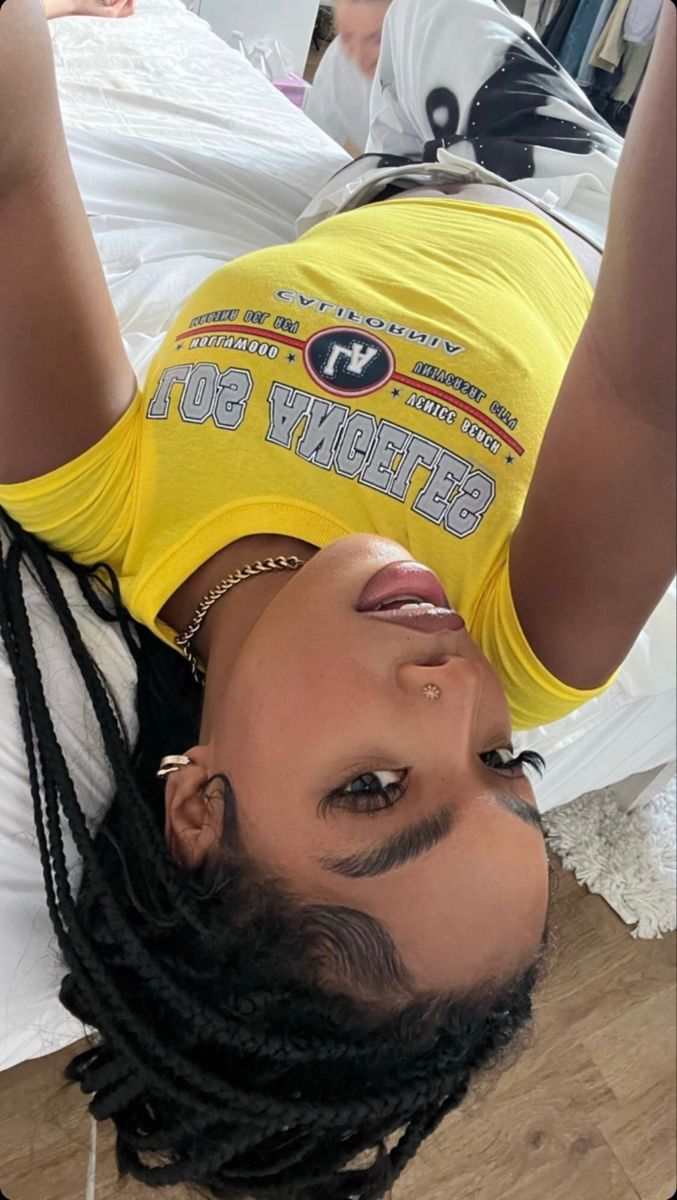 a woman with dreadlocks is laying on the floor wearing a yellow t - shirt