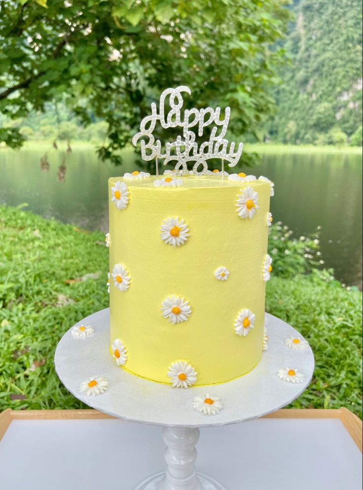 a yellow and white cake with daisies on it