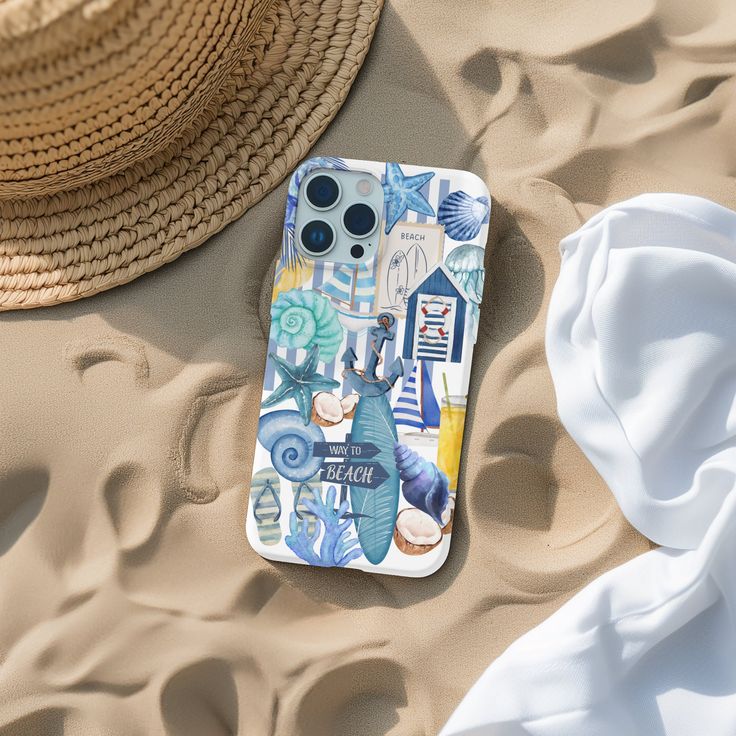 a cell phone laying on top of a sandy beach next to a straw hat and white towel