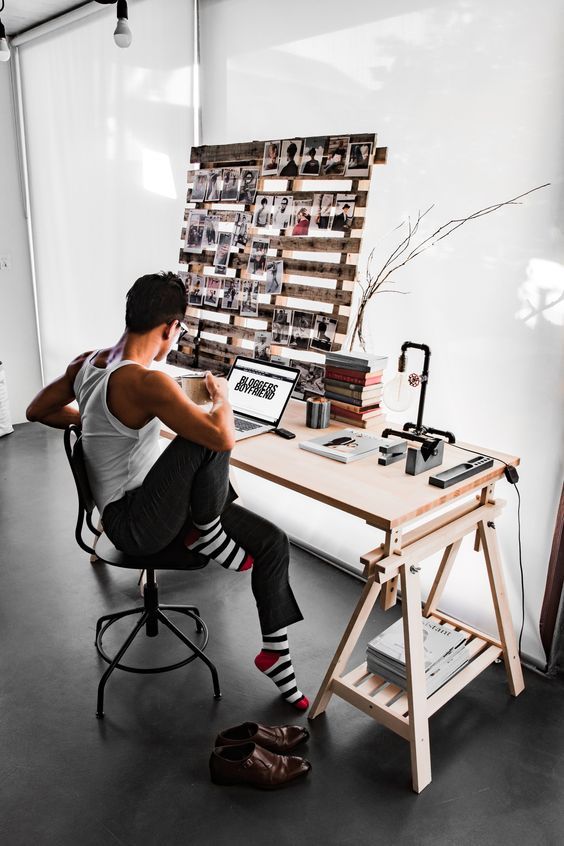 a man sitting at a desk in front of a laptop computer on top of a wooden table