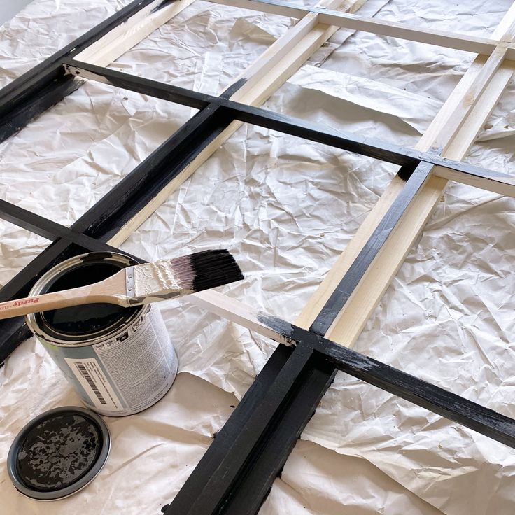 a paint can and brush sitting on top of a piece of wood