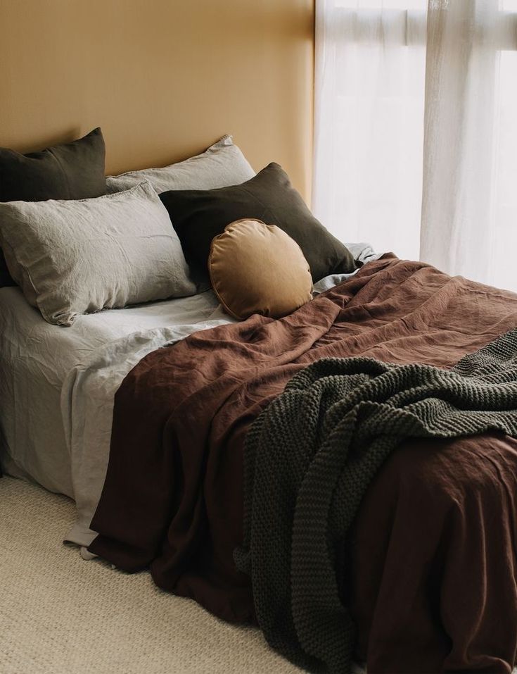 a bed with pillows and blankets in front of a window