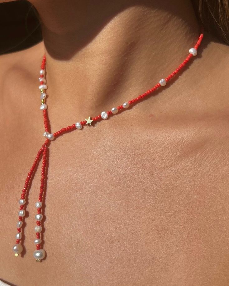 a woman wearing a red beaded necklace with white pearls on it's neck