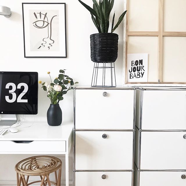 a white desk topped with a computer monitor next to a plant