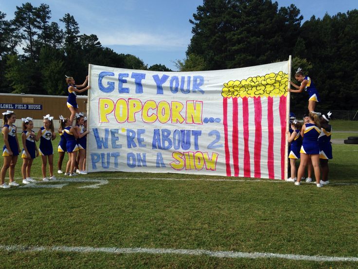 some cheerleaders are standing in front of a sign that says get your popcorn we're about 2 put on a story