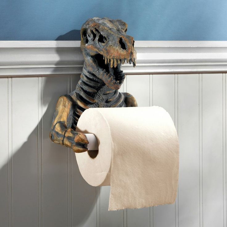 a toy dinosaur holding a roll of toilet paper in it's mouth while hanging on the wall