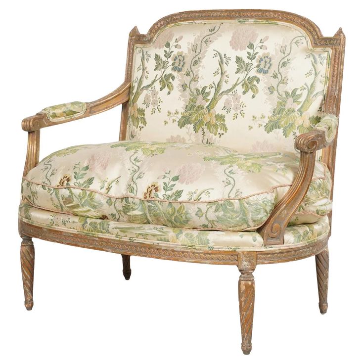 an old fashioned chair with floral fabric and wood trimming on the armrests