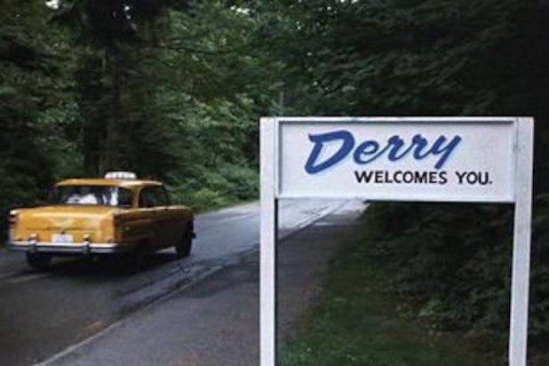 a yellow truck driving past a sign that says derby welcomes you on the road