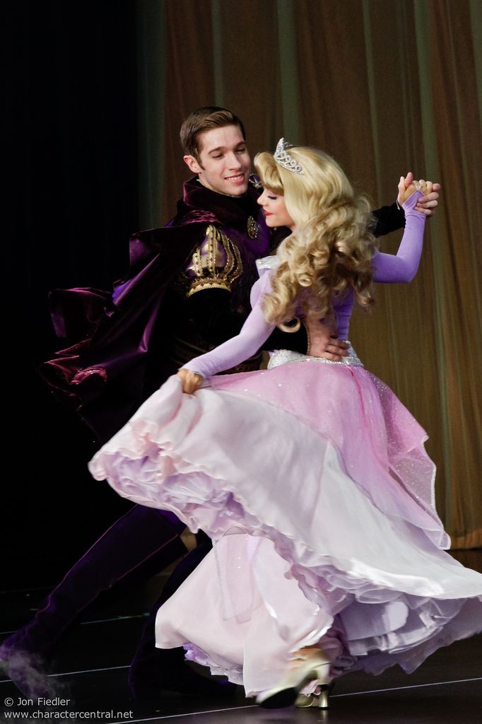 a man and woman dressed in costume dance together on stage with one holding the other's leg