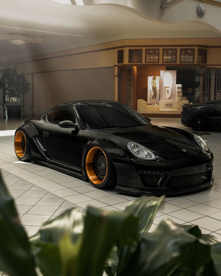 a black sports car parked in front of a building with orange rims on it