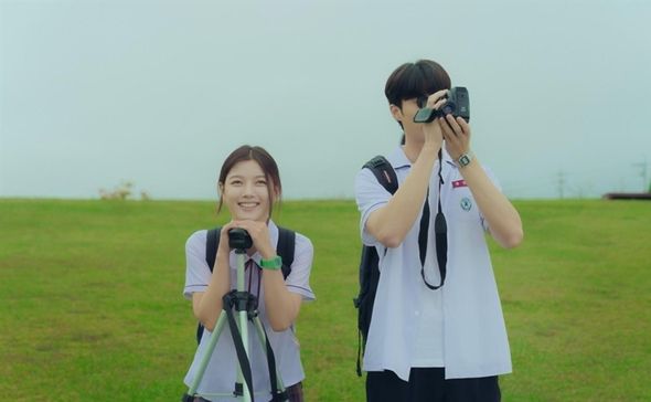 two young people taking pictures with their cameras