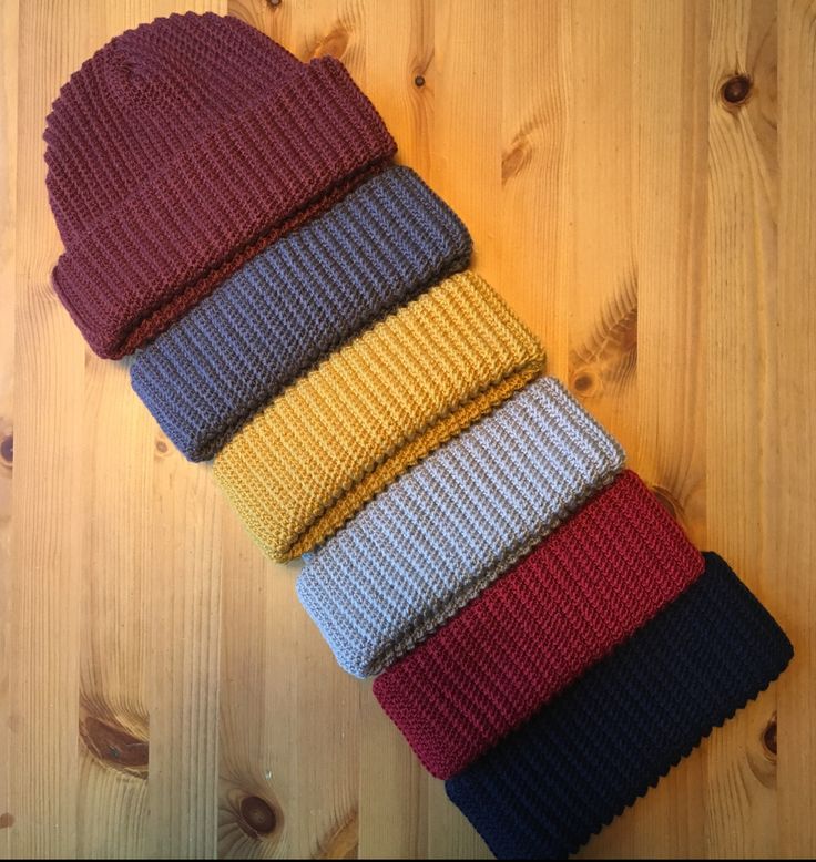 several knitted hats are stacked on top of each other in different colors and sizes