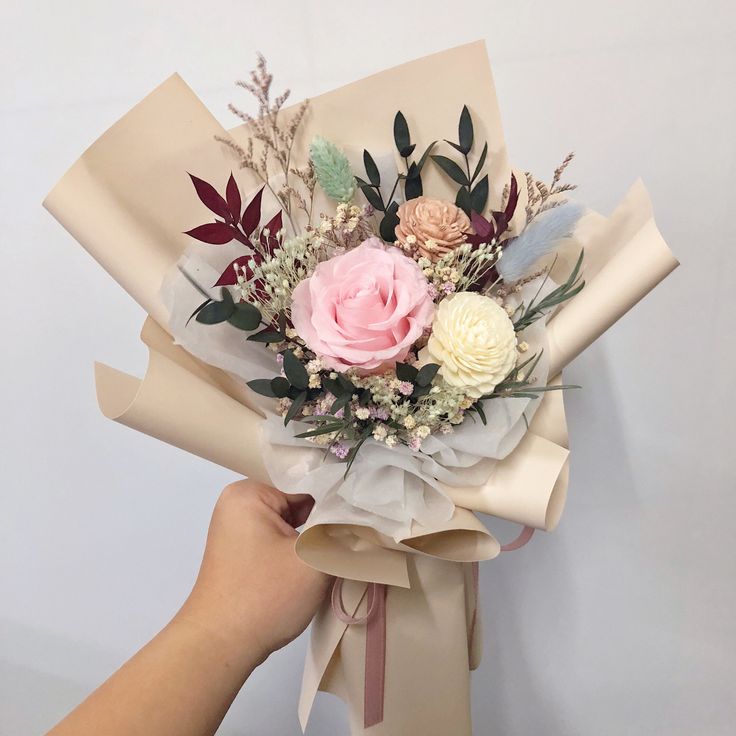 a person holding a bouquet of flowers in their left hand and wrapping it around the other