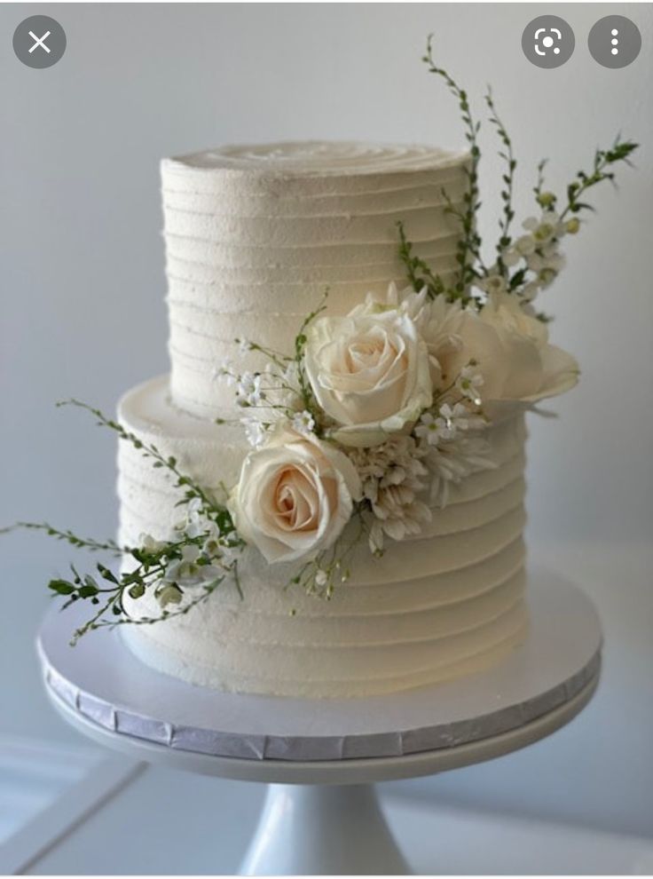 a white wedding cake with flowers and greenery