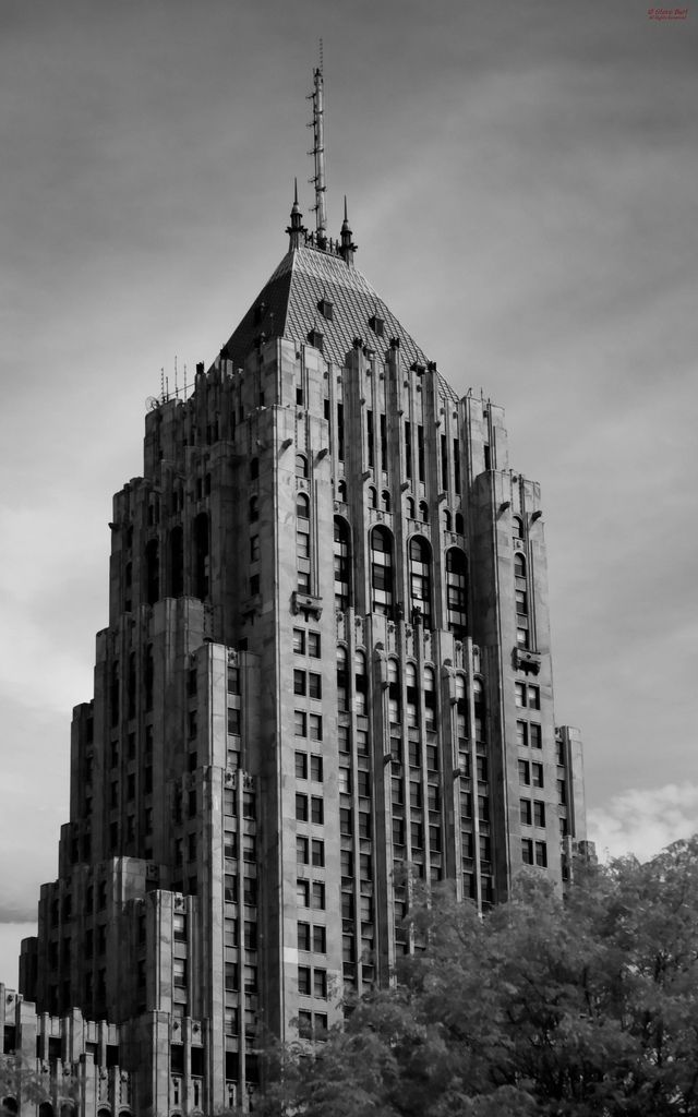 a very tall building that is in the middle of some trees and buildings behind it