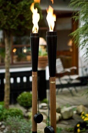 two black candles are lit in the middle of a garden