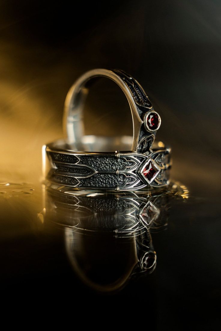 two silver rings sitting on top of a reflective surface with light coming through the background