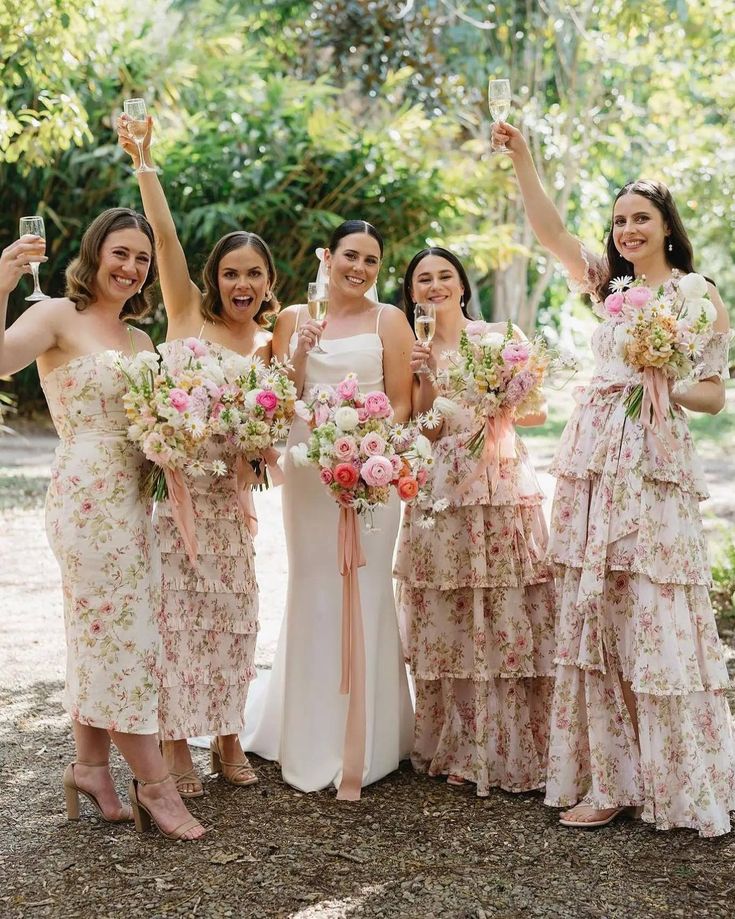 a group of women standing next to each other holding up wine glasses and bouquets