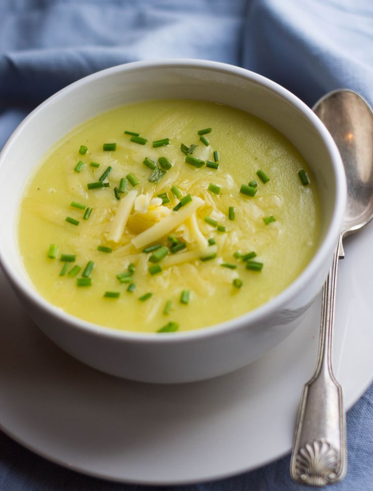 a white bowl filled with soup on top of a plate next to a silver spoon