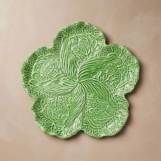 a green flower shaped plate sitting on top of a table next to a brown wall