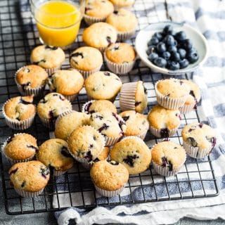 blueberry muffins cooling on a wire rack with orange juice in the background