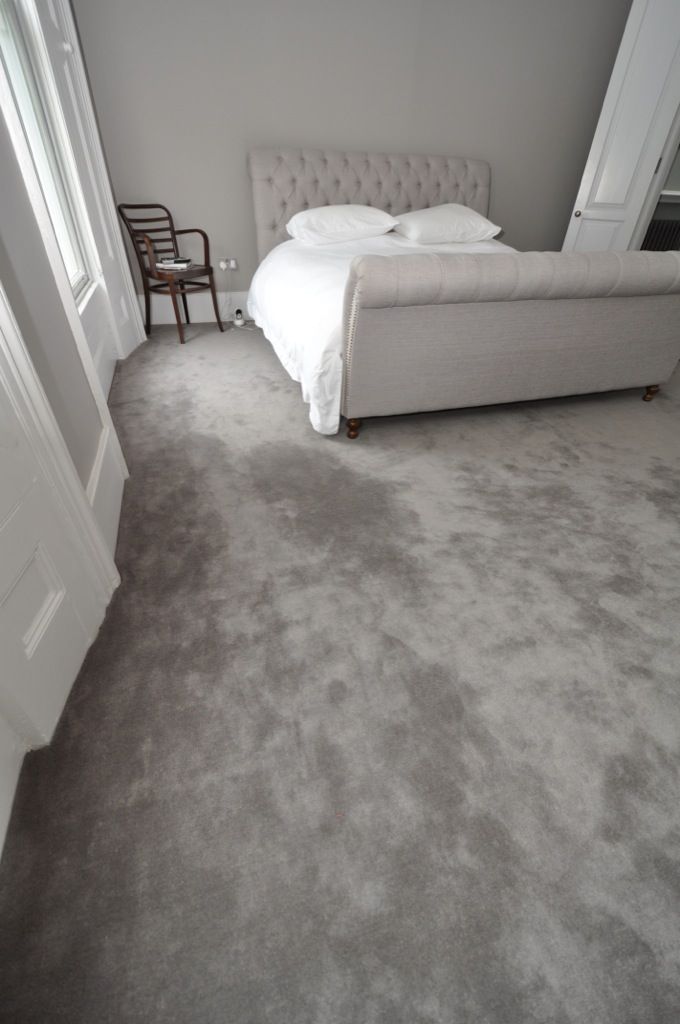 a bed sitting in the middle of a bedroom next to a chair and window on top of a carpeted floor