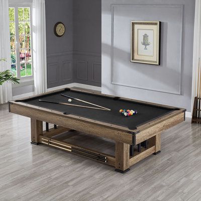 a pool table in the middle of a living room with gray walls and wood flooring