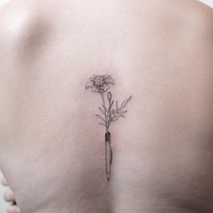 a woman's back with a flower tattoo on her left side ribcage