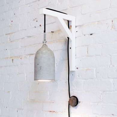 a white brick wall with a light hanging from it's side and a metal hook in the middle