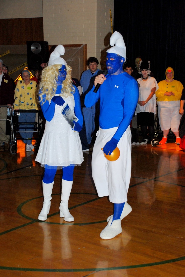 two people dressed as blue men and white women standing on a wooden floor in front of an audience