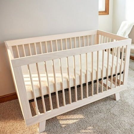 a white crib sitting on top of a carpeted floor next to a window