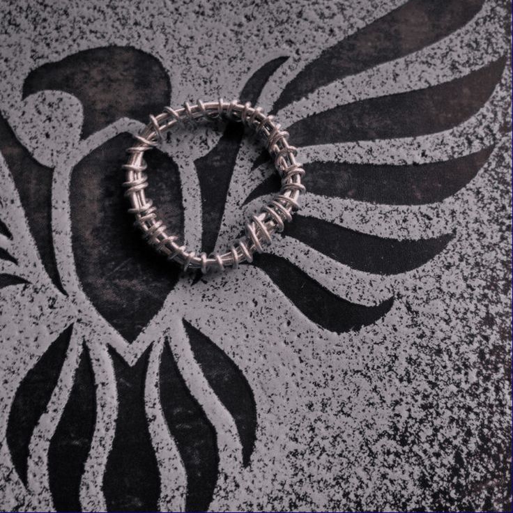 a metal bracelet on the ground with an eagle design painted on it's side