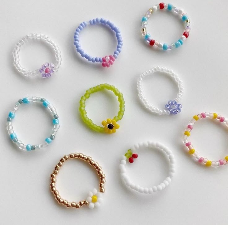 six bracelets are arranged in different colors and sizes on a white surface with beads