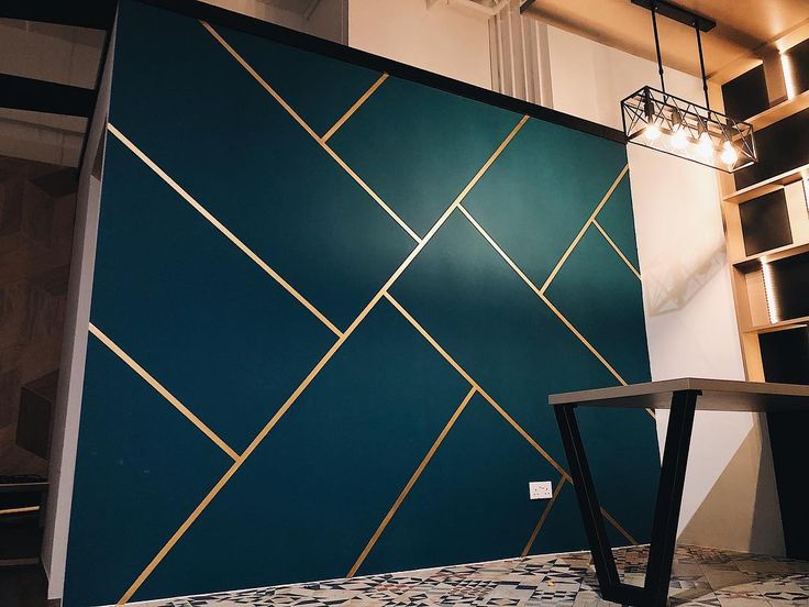 a blue wall with gold lines on it and a wooden table in the foreground