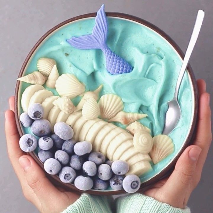 a bowl filled with blue and white food next to a spoon on top of a table