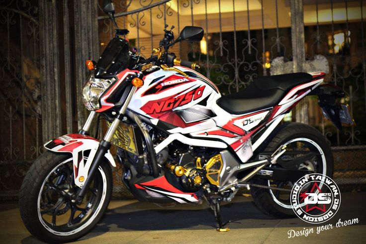 a red and white motorcycle is parked in front of a gated area at night