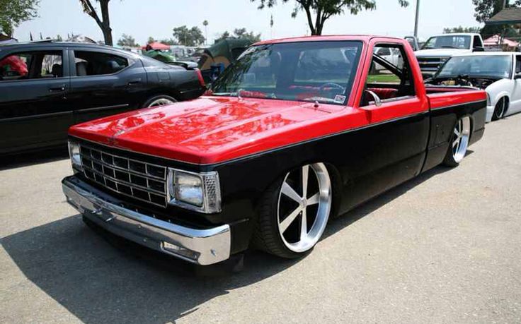 a red and black truck parked next to other cars